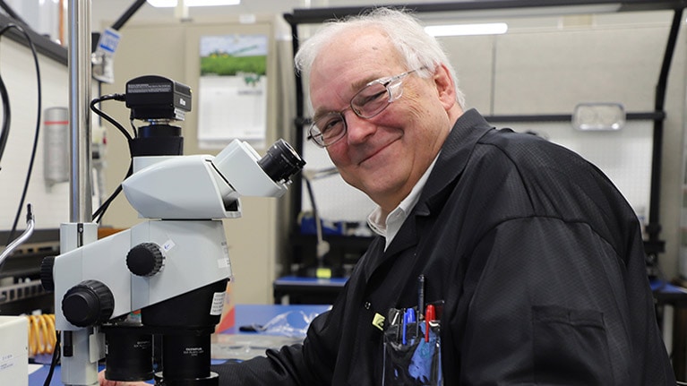 Ο Δρ. William F. Cooper κάθεται δίπλα σε ένα μικροσκόπιο