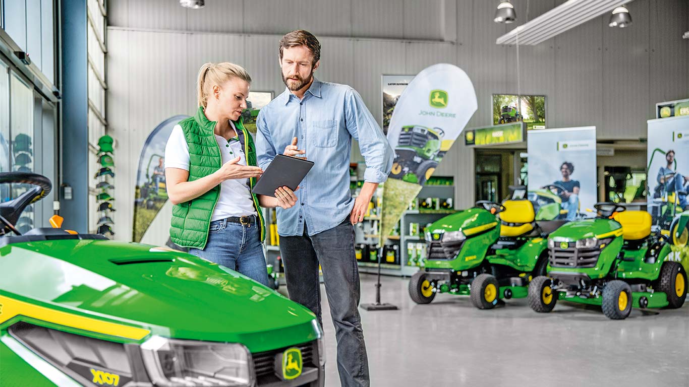 Ένας αντιπρόσωπος της John Deere συμβουλεύει έναν πελάτη για την αγορά ενός χορτοκοπτικού John Deere.