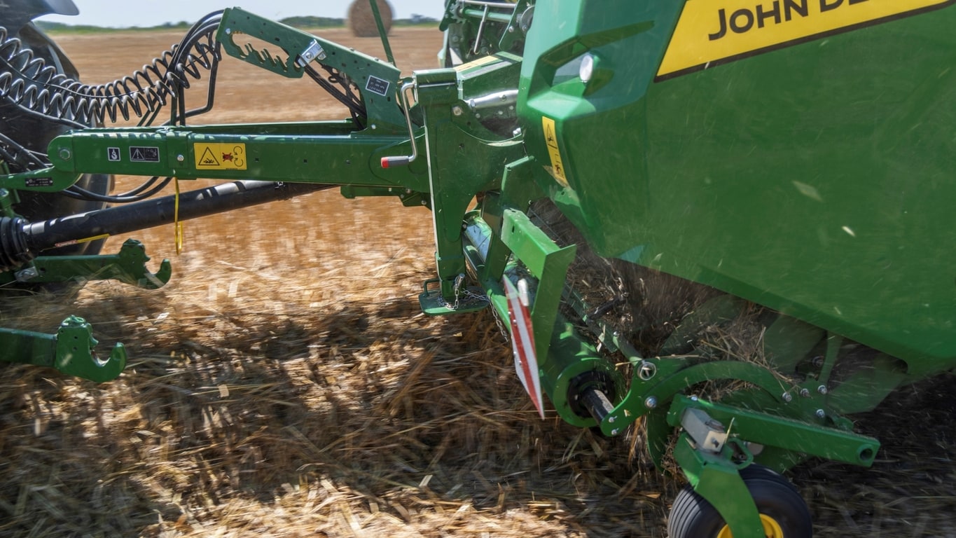 Pick-up υψηλής απόδοσης ενός χορτοδετικού VR της John Deere που εισάγει σε έναν τεράστιο σωρό σταχυών