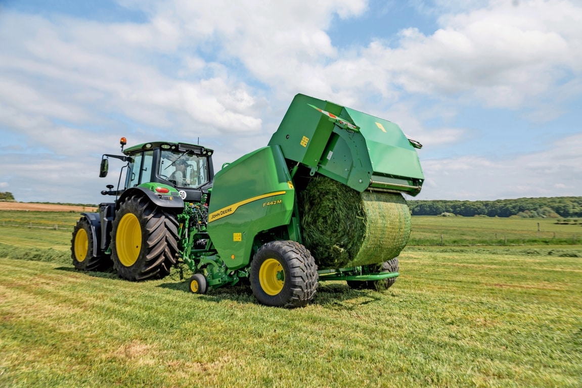 Χορτοδετικό John Deere F442M που ρυμουλκείται από ένα τρακτέρ 6M της John Deere και εξάγει ένα δέμα χόρτου