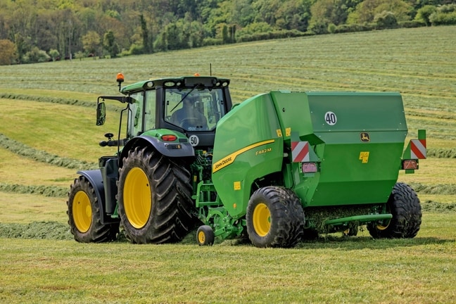 Χορτοδετικό John Deere F442M που ρυμουλκείται από ένα τρακτέρ 6M της John Deere σε λοφώδες χωράφι