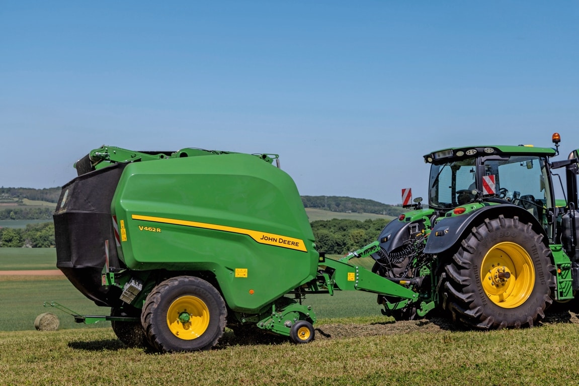 John Deere V462R που ρυμουλκείται από ένα τρακτέρ 6R 185 της John Deere για σχηματισμό δεμάτων σανού